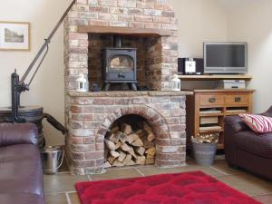 a brick fireplace with a stove in a living room at The Old Forge in West Lutton