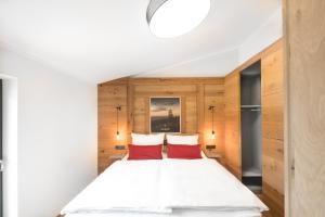 a bedroom with a white bed with two red pillows at Chalet-Ferienwohnung Bergloft, 115 qm, Wellness/Fitness/Sauna – Bergrödelhof in Feilitzsch