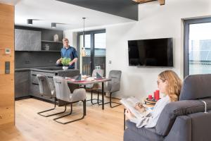 a man standing in a living room with a kitchen at Chalet-Ferienwohnung Bergloft, 115 qm, Wellness/Fitness/Sauna – Bergrödelhof in Feilitzsch