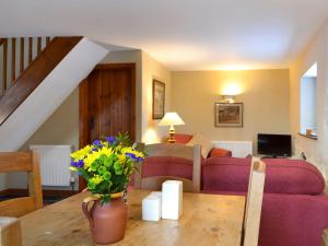 a living room with a couch and a table with flowers at Grange Farm Cottage in Barton in the Clay