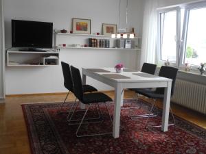 een witte eettafel met stoelen en een televisie bij Ferienwohnung Grob "Seeblick" in Konstanz