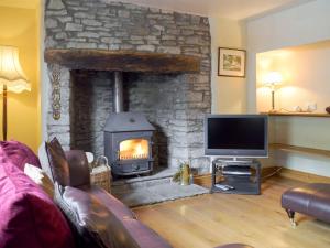 uma sala de estar com uma lareira de pedra e uma televisão em The Oak em Newchurch
