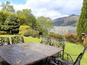 a table and chairs with a view of a lake at Feaugh Cottage in Lochgoilhead