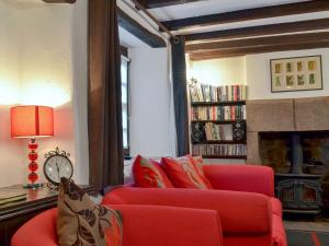 a living room with a red couch and a fireplace at Cornerpin Cottage in Crich