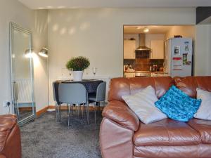 a living room with a brown leather couch and a kitchen at Llwyn Rhedyn in Blaenau-Ffestiniog