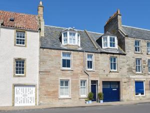 an old brick building with white windows and blue doors at St Andrews in Pittenweem