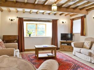 a living room with a couch and a tv at Ty Rhyd in Llanrhaeadr-ym-Mochnant