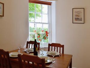 uma mesa de jantar com uma garrafa de vinho e uma janela em Dunlappie Lodge em Edzell