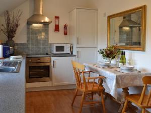 cocina con mesa con sillas y microondas en Maplehurst Barn Stables, en Staplehurst