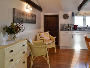 una cocina con armarios y sillas blancos y una mesa. en Maplehurst Barn Stables, en Staplehurst