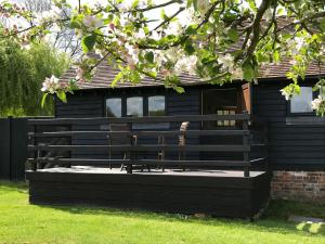 una casa negra con un banco delante en Maplehurst Barn Stables, en Staplehurst