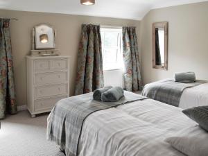 um quarto com 2 camas, uma cómoda e um espelho em Halfehill Cottage em Richmond