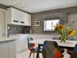 a kitchen with a table with a vase of flowers at Lowther Cottage in Clifton