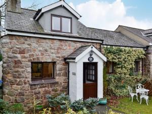 a stone house with a brown door and chairs at Oakleigh Cottage in Llangelynin