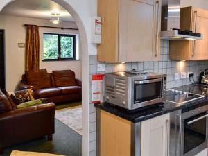 a kitchen with a microwave and a living room at Oakleigh Cottage in Llangelynin