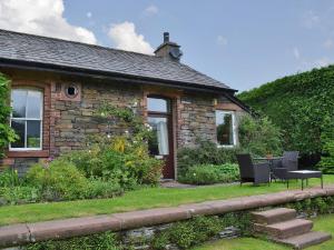 a stone house with a table and chairs in front of it at Ticket Office in Torver