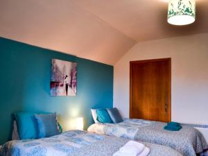 two beds in a room with blue walls at Bluebells in Strathpeffer