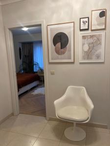 Cette chambre comprend une chaise blanche et des photos sur le mur. dans l'établissement Logies Windsor One Room, à Ostende