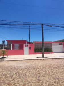 un edificio rosa con dos puertas de garaje en una calle en Pousada da Dinda - Casa Familiar, en São Gabriel