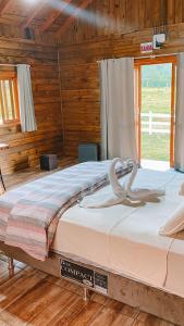 uma cama grande num quarto de madeira com uma janela em Cabana Furna dos Pôneis em Urubici