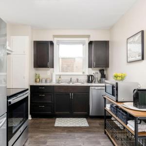 a kitchen with black cabinets and a sink at Bexley Breeze, Fast Wi-Fi, King Bed in Bexley
