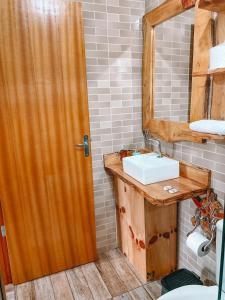a bathroom with a sink and a wooden door at Cabana Furna dos Pôneis in Urubici