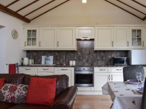 uma cozinha com armários brancos e um sofá em Pipers Stable em Nether Stowey