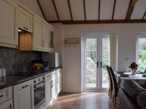 uma cozinha com armários brancos e uma grande janela em Pipers Stable em Nether Stowey