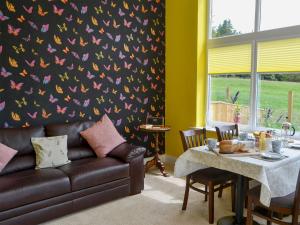 a living room with a couch and a table with a butterfly wallpaper at Squirrel Cottage in Sharperton