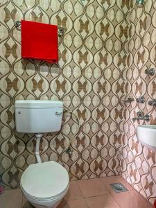 ein Badezimmer mit einem WC und einer roten Box an der Wand in der Unterkunft Tiger Corner Inn Homestay in Sauraha