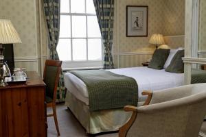 a hotel room with a bed and a chair at Old Hunstanton Le Strange Arms Hotel in Hunstanton