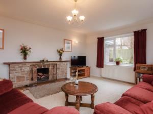a living room with a fireplace and red furniture at Orchard Well in Winscombe
