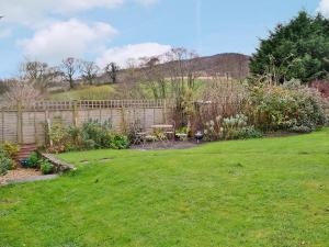 a garden with a fence and a table in a yard at Barters Cottage in Chideock