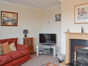 ein Wohnzimmer mit einem roten Sofa und einem Flachbild-TV in der Unterkunft Samphire in Brixham