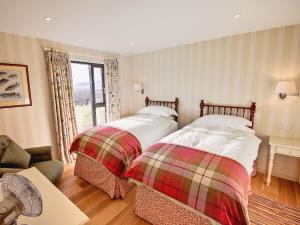 a bedroom with two beds and a living room at Phils House in Lairg