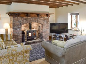 a living room with a brick fireplace and a tv at Buddileigh Farm in Betley