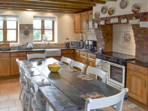 une cuisine avec une grande table et des chaises en bois dans l'établissement Buddileigh Farm, à Betley