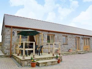 een stenen cottage met een tafel en een parasol bij The Dairy - Op3 in Carmarthen