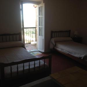 a bedroom with two beds and a door to a balcony at Les arcades in Moissac-Bellevue