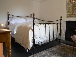 a bedroom with a bed with white sheets and a fireplace at Church Walk Cottage in Kendal