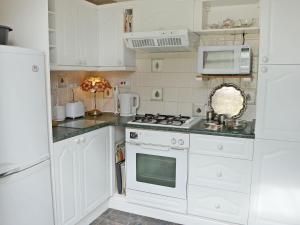 a white kitchen with a stove and a microwave at Tudor Cottage in Ainsdale