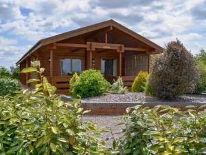 a small wooden cabin with a porch in a garden at Willow Lodge in Burgh le Marsh