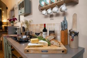 a kitchen counter with a cutting board with bread and wine at The Old Parlour at Cheshire Boutique Barns in Nantwich