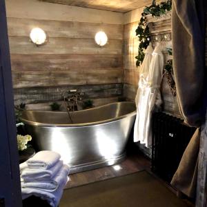 a bath tub in a bathroom with wooden walls at The Old Parlour at Cheshire Boutique Barns in Nantwich