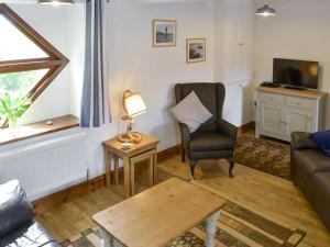 a living room with a couch and a chair and a table at Red Barn Cottage in Kettleburgh