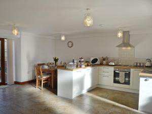 a kitchen with white cabinets and a table in it at Ysgubor-w43383 in Cilybebyll