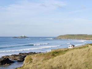 a small white house on a hill next to the ocean at The Old Dairy in Mount Hawke