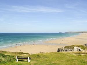 un banco en una colina con vistas a una playa con gente en The Old Dairy en Mount Hawke