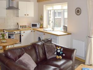 a living room with a leather couch in a kitchen at The Shippon in Pancrasweek