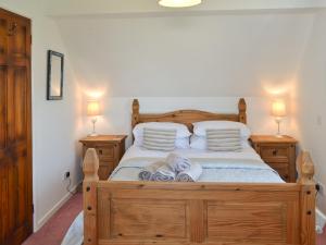 a bedroom with a wooden bed with towels on it at Grey Cottage in Pentraeth